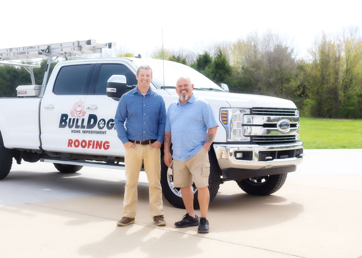 Image of owner Chris and owner John in font of company truck